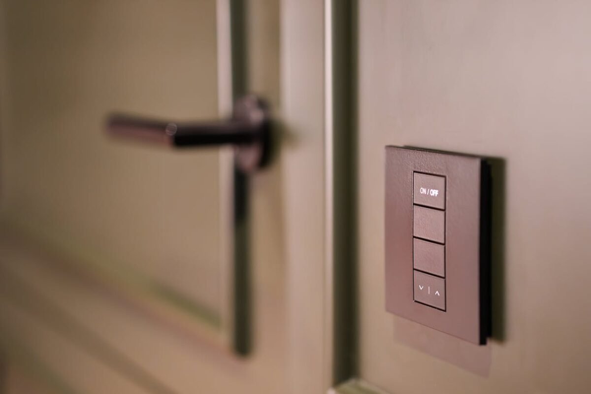 A smart light switch on a wall next to a modern door handle, emphasizing home automation.