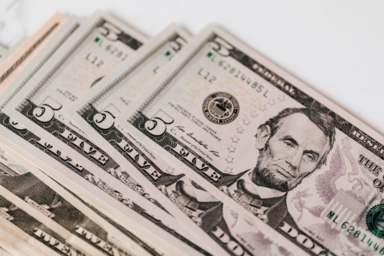 High-quality image of five dollar bills in a neat stack, representing currency and financial concepts.