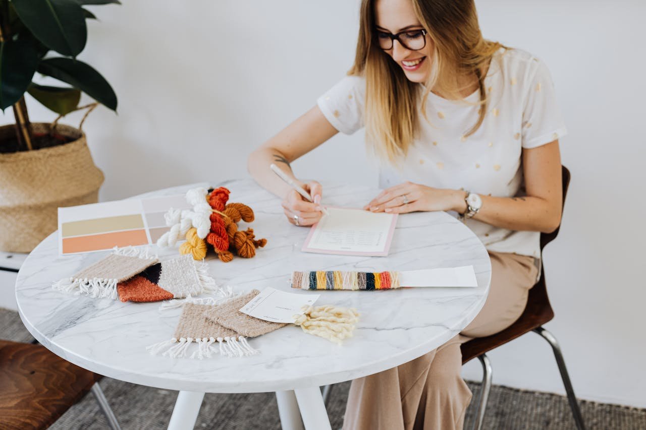 Creative woman crafting designs with color samples and yarn on a round table indoors.