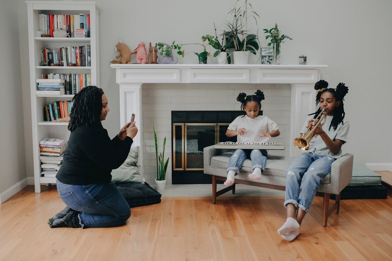 Mother capturing daughter and son playing keyboard and trumpet indoors.