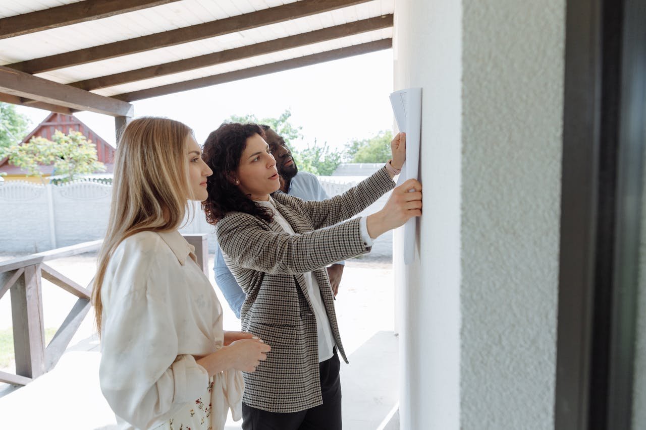 Group of adults discussing and reviewing paper plans during a business meeting outdoors.